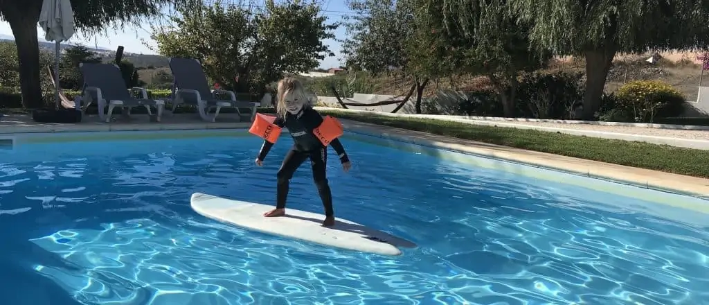 Small child having fun on a surfboard in the pool of Ericeira Surf House