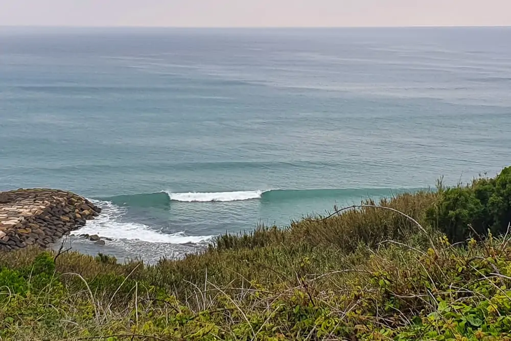 A lefthand wave breaking off the jetty at Papucos just south of Ericeira