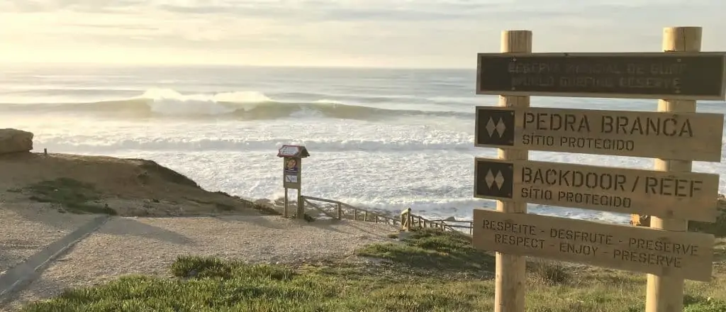 Sign of the World Surfing Reserve with the wave of Pedra Branca breaking in the background