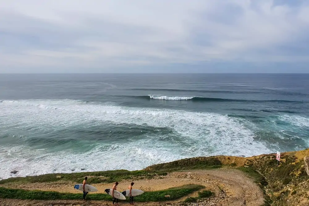 Surfers walking down the dirt road at Praia Pequena in Sintra