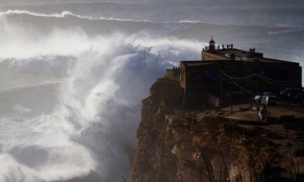 Giant waves breaking in front of the lighthouse in Nazaré